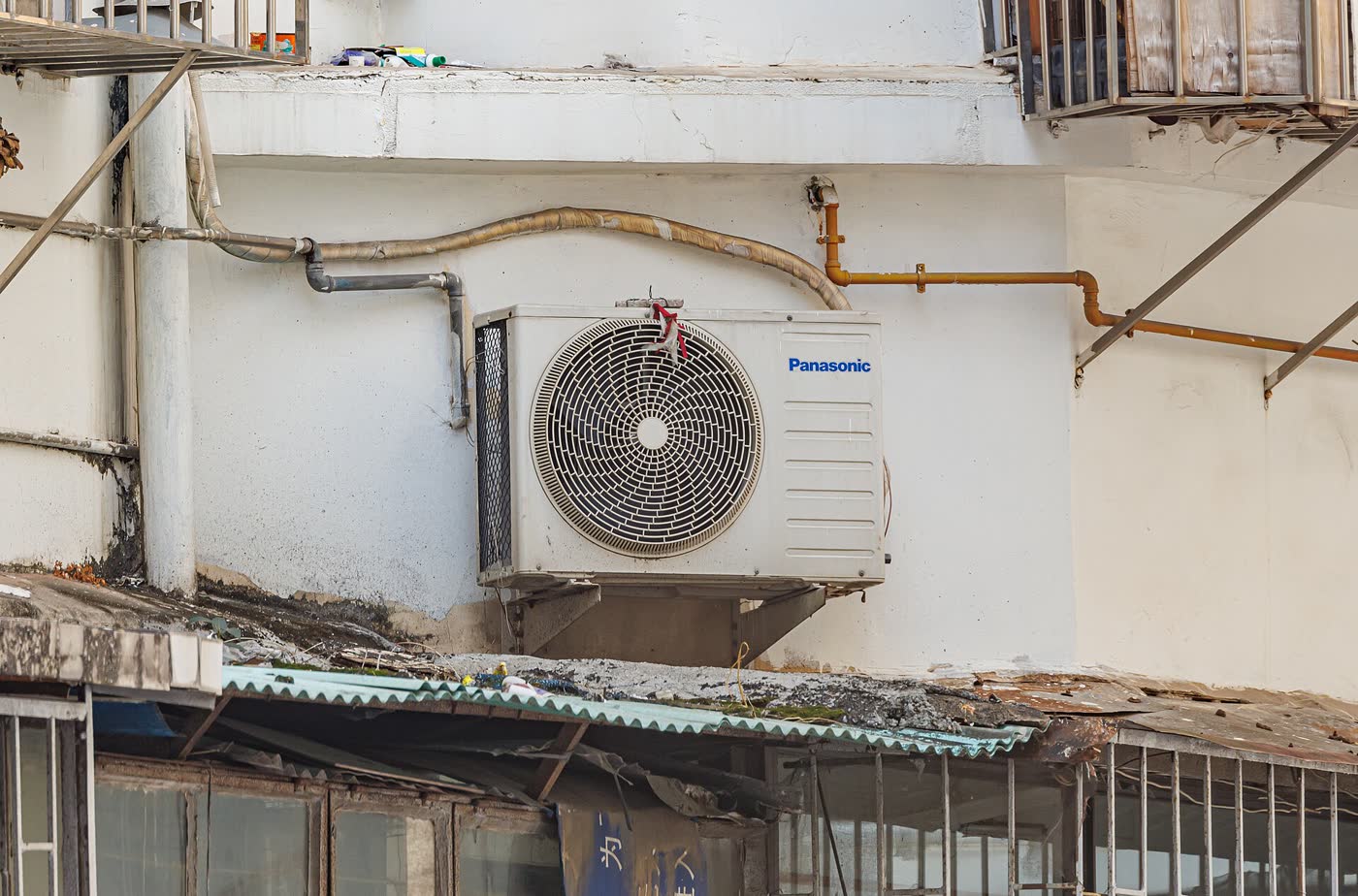 Unidad exterior de aire acondicionado montada con soportes en la fachada de un edificio
